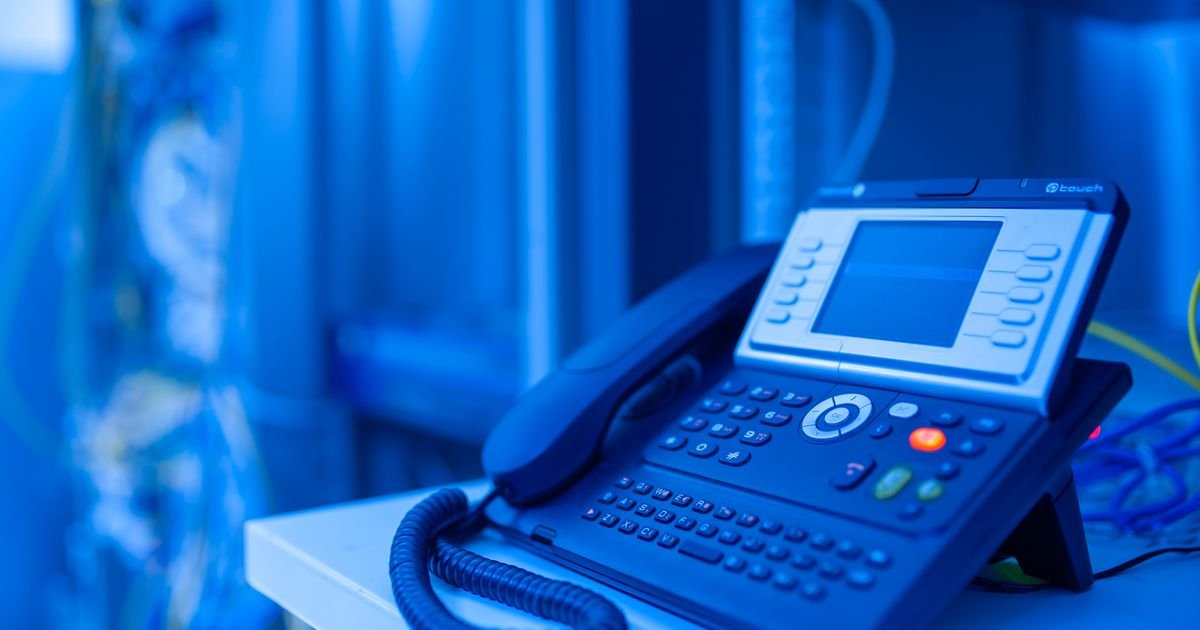 Téléphone IP d'entreprise dans une salle télécom aux tons bleus, illustrant la migration des autocommutateurs RNIS vers la voix sur IP avant la fin du cuivre